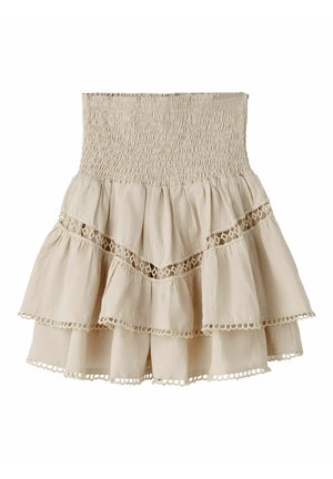 Béžová vrstvená mini sukňa s naberaným vysokým pásom, krajkovými detailmi a dvojitými volánmi na jednoduchom bielom pozadí.