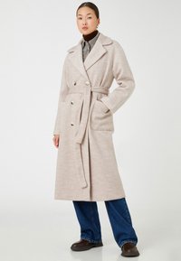 Hellebeige, doppelt knöpfbarer Wollmantel mit großen Knöpfen, einem Gürtel und seitlichen Taschen; verfügt über einen Reverskragen und eine entspannte Passform.