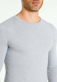 T-shirt a maniche lunghe grigio chiaro con colletto rotondo. Realizzato in un tessuto morbido e strutturato, con una vestibilità slim che si adatta al corpo.