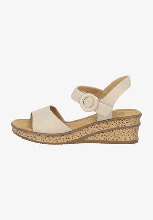 Sandalias de cuña beige con una parte superior de cuero suave, una correa de tobillo ajustable con un acento circular y una suela de textura similar al corcho.