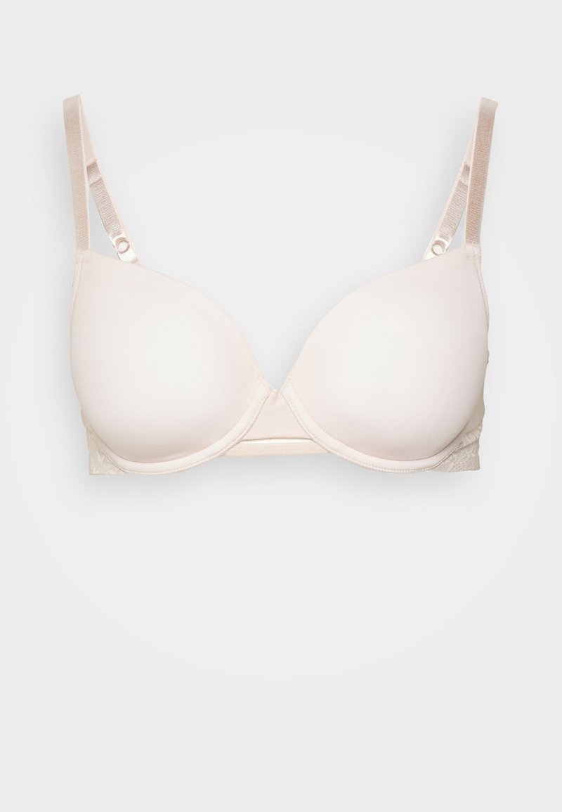 Reggiseno imbottito beige con spalline regolabili e ferretto, con coppe lisce e dettaglio in pizzo sui lati su uno sfondo bianco.