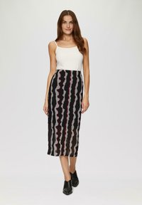 Jupe midi à motifs noir et gris avec un design ondulé, associée à un débardeur blanc. Le tissu est transparent avec une texture en couches notable.