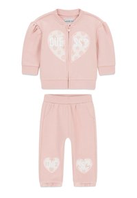 Lichtroze kindertrainingspak met een jas met rits, pofmouwen en een hartje, gecombineerd met bijpassende broek en ingestikte manchetten.