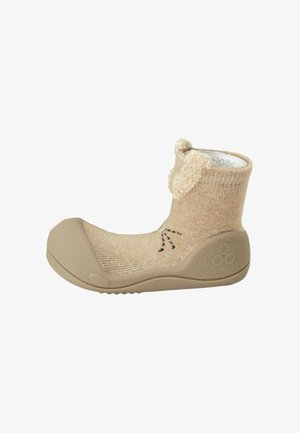 Morbida scarpa beige per bambino con suola in gomma flessibile, tomaia lavorata a maglia e ricamo con faccia di orso e orecchie sul polsino alla caviglia.