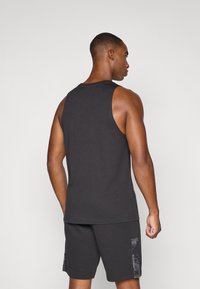 Zwarte sportieve tanktop met een ronde hals en mouwloos design, gecombineerd met zwarte shorts met een gestructureerde zijkant.
