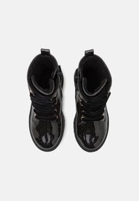 Botas de tobillo negras con un acabado brillante y brillante. Las características incluyen una punta redonda, cordones delanteros y ojales y acentos en oro rosa.