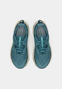 Türkiissinised jooksujalatsid tekstureeritud võrgust ülaosaga, beežid detailid ning kummist tald. Omavad lamedaid paelu ja tõmbenööri lihtsaks jalga panekuks.