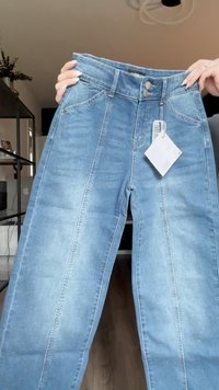 Svetlo modri traper jeans z visokim pasom, dvema gumboma za zapiranje in stranskima žepoma. Imajo ravno nogo z zbledelim videzom.