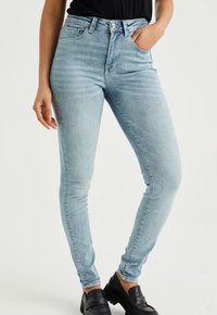 Ljusblå högmidjade skinny jeans i denim; har framfickor, knäppning med knapp och en slät yta.