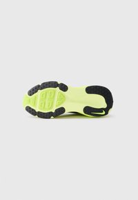 Semelle de chaussure de sport noire et jaune fluo avec un design texturé, des motifs de grip en caoutchouc et une forme lisse et allongée.