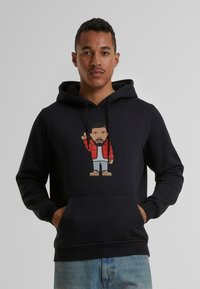 Zwarte hoodie met een Franse zak, versierd met een cartoonafbeelding van een persoon in een rode pufferjack en lichtblauwe broek. Zacht materiaal, standaard pasvorm.