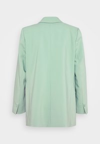 Blazer vert clair sur mesure vu de dos avec manches longues et poignets boutonnés.