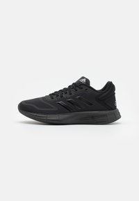 Scarpa da corsa Adidas nera con tomaia in mesh, chiusura con lacci, tre strisce nere sui lati e suola ammortizzata su sfondo bianco.