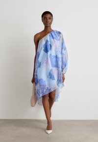 Enaxelklänning i ljusblå chiffon med lila blommönster, asymmetrisk fåll och en flödande, genomskinlig textur.