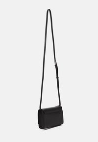 Čierna kožená crossbody taška s hladkou textúrou, obdĺžnikovým tvarom a dlhým nastaviteľným popruhom. Obsahuje klopňové uzatváranie a minimálne kovové doplnky.