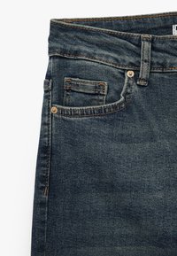 Mörkblå denimjeans med en klassisk femfickedesign, med gyllene stygn och en liten myntficka framtill.