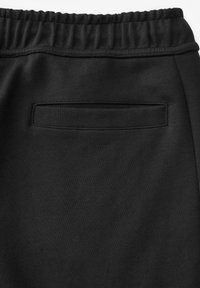 Sorte sweatpants med en glat tekstur, med en elastisk talje og en flad baglomme uden synligt hardware eller accenter.