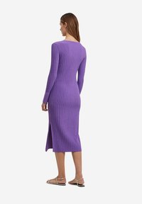 Abito a maglia ribbed viola con maniche lunghe e spacco laterale, caratterizzato da un design aderente e scollatura a girocollo. Dettagli includono un tessuto testurizzato.