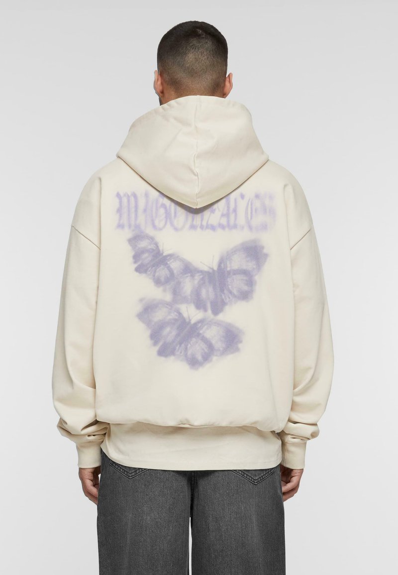 Creme hoodie med et stort, lilla sommerfuglegrafik på ryggen, der har en afslappet pasform og rummelig hætte. Fremstillet af blødt stof.