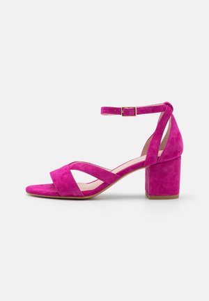Sandale pour femme en daim rose avec talon bloc, bout ouvert, brides croisées et fermeture à boucle réglable à la cheville.