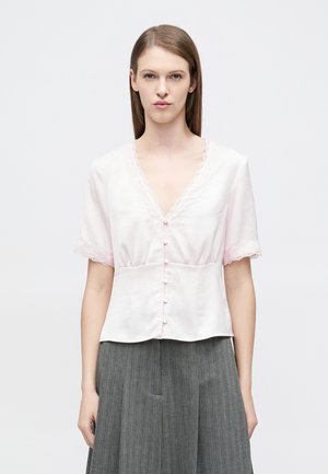 Ροζ σατέν μπλούζα με κοντά μανίκια διακοσμημένα με δαντέλα, ντεκολτέ σε σχήμα V και διακοσμητικά κουμπιά κατά μήκος του εμπρός μέρους. Λεία υφή και εφαρμοστό σχέδιο.