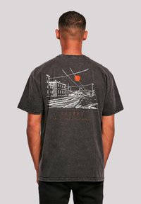 Black graphic t-shirt featuring a white cityscape illustration and red sun on the back. Short sleeves and relaxed fit, with visible stitching details.