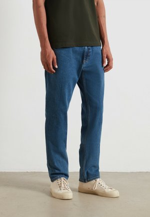 Blauwe denim jeans met een rechte pijp, met een middelhoge taille en subtiele stiksels. Draag het met beige canvas sneakers.