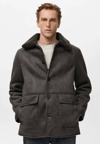 Cappotto grigio scuro con bottoni e colletto in tessuto testurizzato, caratterizzato da due tasche anteriori e un design semplice.