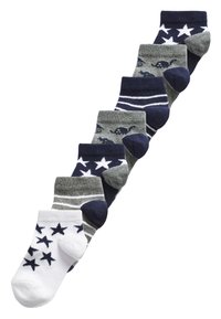 Syv par ankelsokker med forskellige designs i hvid, navy og grå. Mønstret inkluderer stjerner og striber, med ribbede manchetter.