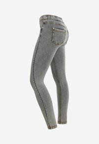 Jeans skinny grigi a vita alta con tasche posteriori e cuciture arancioni, mostrati da un angolo laterale posteriore su sfondo bianco.