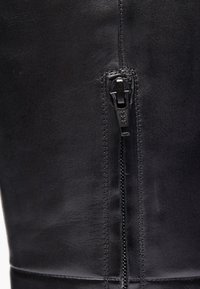 Čierna kožená obuv s bočným zipsom, matnou textúrou, prešitými detailmi a elegantným dizajnom. Zips je značkový YKK.
