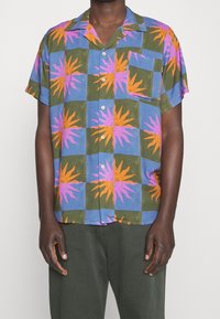 Koszula z krótkim rękawem zapinana na guziki, z wzorem patchworkowym z motywami słońca w odcieniach pomarańczowym i różowym na niebiesko-zielonym tle. Wykonana z bawełny.