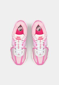 Nike Vomero 5 tenisice u svijetlo ružičastoj boji sa mrežastim gornjim dijelom, bijelim vezicama, srebrnim detaljima i okruglim crnim logom na unutrašnjem dijelu jezika.