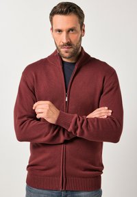 Burgundská zip-up cardigan vyrobená z texturované pleteniny, s vysokým límcem a žebrovanými manžetami a lemováním. Jednoduchý design, bez vzorů nebo akcentů.