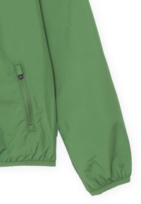 Giacca leggera verde con maniche lunghe, polsini elasticizzati e una tasca con zip. Texture liscia e design semplice senza motivi.