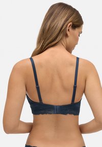 Sujetador azul sin aros con banda de encaje, tejido suave, tirantes ajustables y cierre de gancho y ojo en la parte posterior.