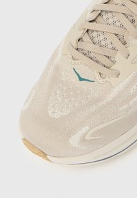 Μπεζ αθλητικό πα πούτσι με υφασμένο επάνω μέρος με υφή, σχεδιασμό κορδονιών, τυρκουάζ λεπτομέρεια και εξωτερική σόλα από καουτσούκ χρώματος καραμέλα. Διαθέτει οπές αερισμού για καλύτερη αναπνοή.