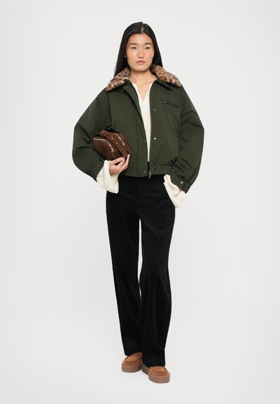 Žalias bomberis su leopardų rašto pūkine apykakle, balta palaidinė, juodos velveto kelnės, rudas rankinukas ir tan spalvos platforminiai bateliai.