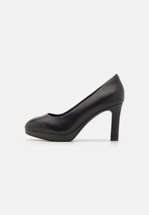 Zwarte leren damesschoenen met hoge hak, een afgeronde neus en plateauzool, zijaanzicht op een lichtgrijze achtergrond.