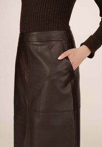 Gonna in pelle marrone scuro con una texture liscia, vita alta e dettagli con tasche laterali. Cuciture a vista sulla superficie.