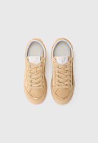 Beige Wildleder-Sneaker mit goldenen Akzenten, runder Spitze, flachen Schnürsenkeln und weißem Futter. Verfügt über ein dreieckiges Logo auf der Zunge.