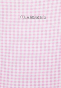 Różowo-biała tkanina w kratkę w małym szarym haftowanym logo "CLAESEN'S" umieszczonym na górze. Lekka bawełniana tekstura.