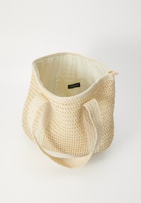 Borsa di paglia intrecciata di forma rotonda, di colore beige e foderata in tessuto. Caratterizzata da manici corti e chiusura con zip. Etichetta interna visibile.