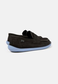 Scarpe slip-on in suede marrone scuro con suola in gomma blu chiaro e una lavorazione intrecciata sulla parte superiore per un tocco di texture e design.