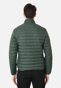 Giacca a vento verde con design trapuntato, colletto rialzato e maniche lunghe. Presenta una texture di tessuto liscia e lucida e una silhouette aderente.