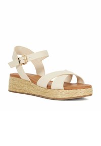 Witte leren wedge sandalen met kruisbandjes, een gespsluiting rond de enkel en een natuurlijk geweven jute plateau voor extra hoogte en textuur.