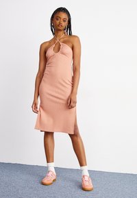 Abito midi pink a coste e senza maniche con scollatura a chiave, spacco laterale e collo a halter. Indossato con sneakers rosa e calze bianche.