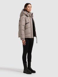 Dunjakke i lysegrå med hætte, med quiltet tekstur, sidelommer og lynlås foran. Kombineret med sorte leggings og støvler.