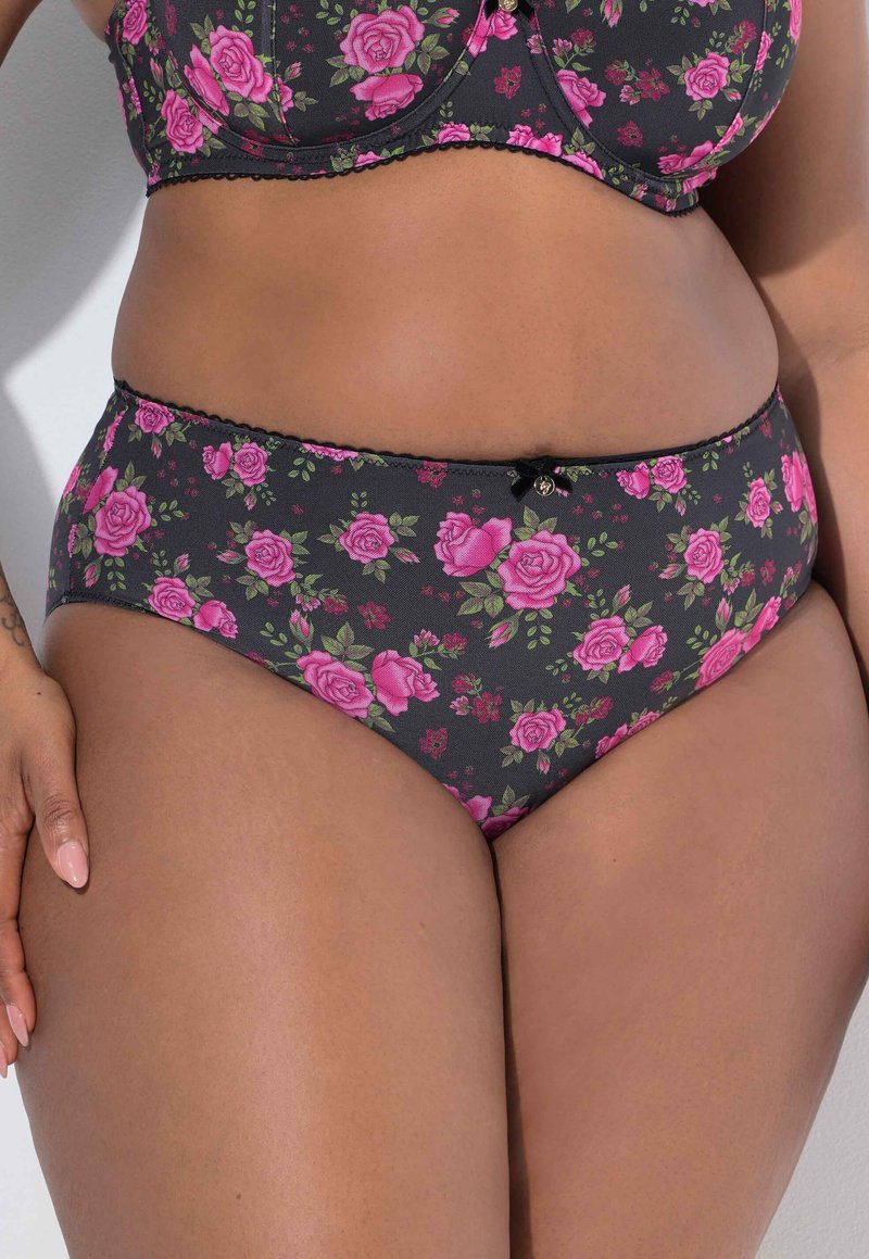 Zwarte slip met bloemenprint met roze rozen en groene bladeren, voorzien van een getand taillebandje en een klein decoratief strikje aan de voorkant.