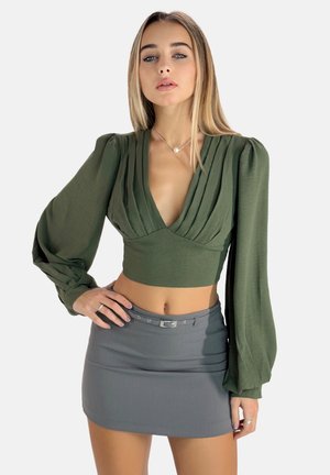 Olive green cropped blouse with pleated design and long puff sleeves, paired with a fitted gray mini skirt featuring a belt.